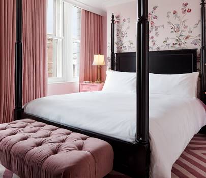 The bedroom of the First Lady Ida McKinley suite, showcasing elegant floral wall designs and luxurious bedding.