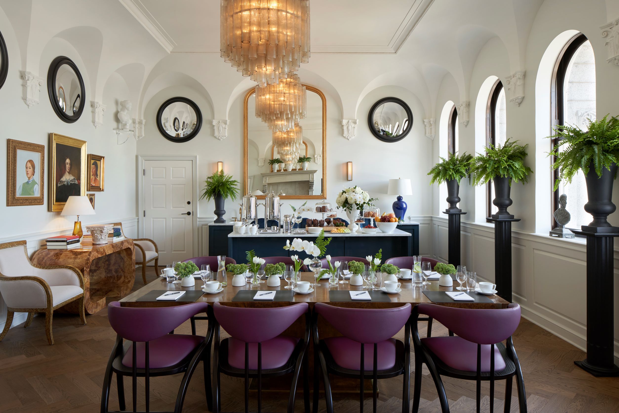 A lavishly set dining table in a meeting room with a buffet in the background