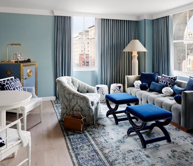 Living room with blue and white decor, including a comfortable sofa, blue chairs, a vsafe, and a decorative wall.