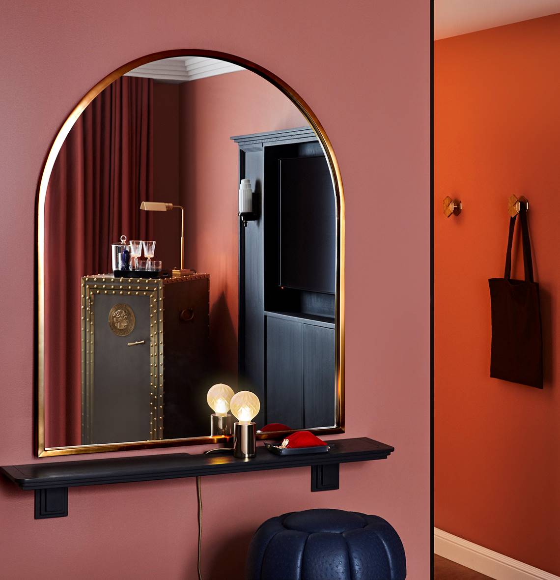 An ornate mirror in a guest room at Riggs DC, showcasing intricate detailing and elegant design on a pink wall.