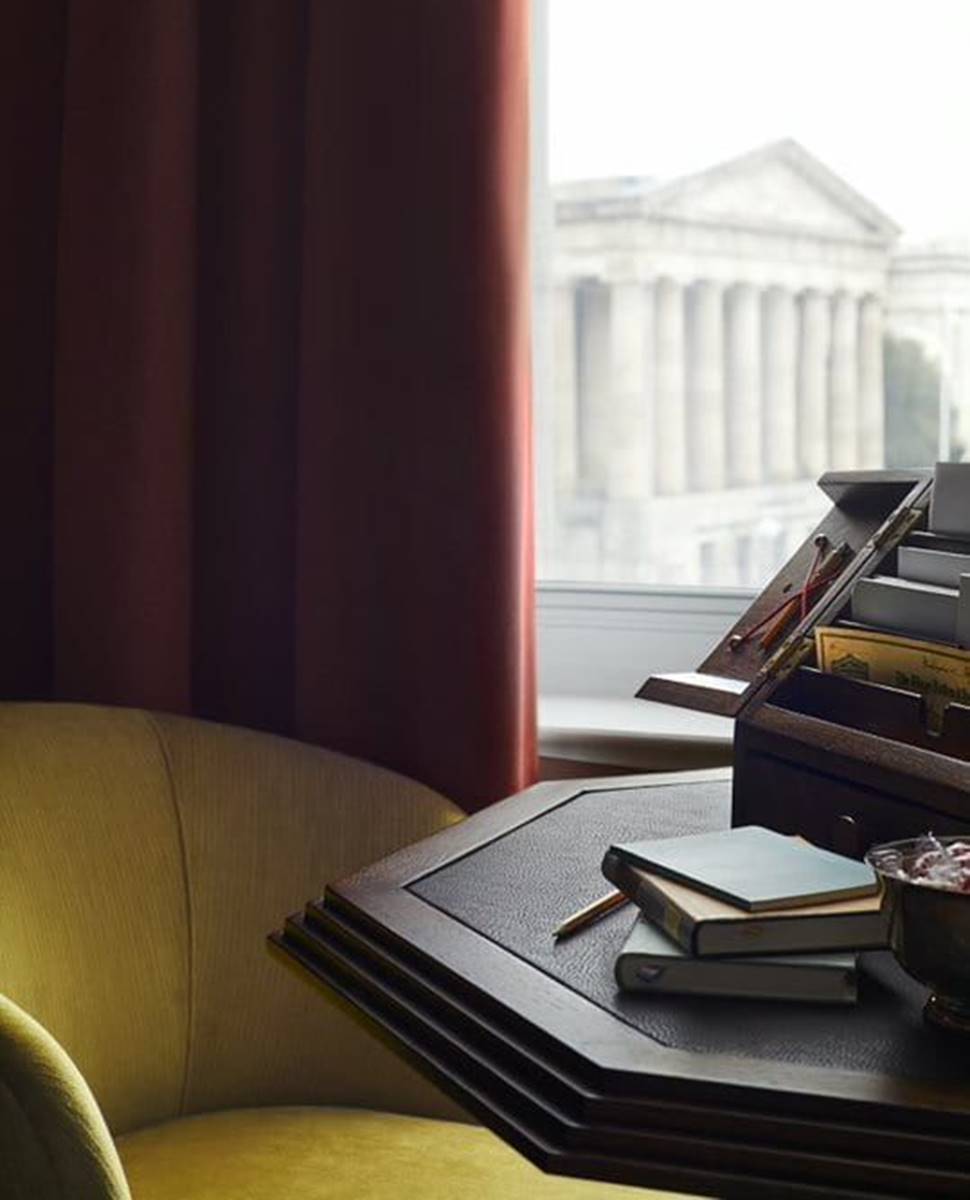 A hotel room detail at Riggs DC with a yellow chair, a wooden table and a beautiful view to the historic city centre.