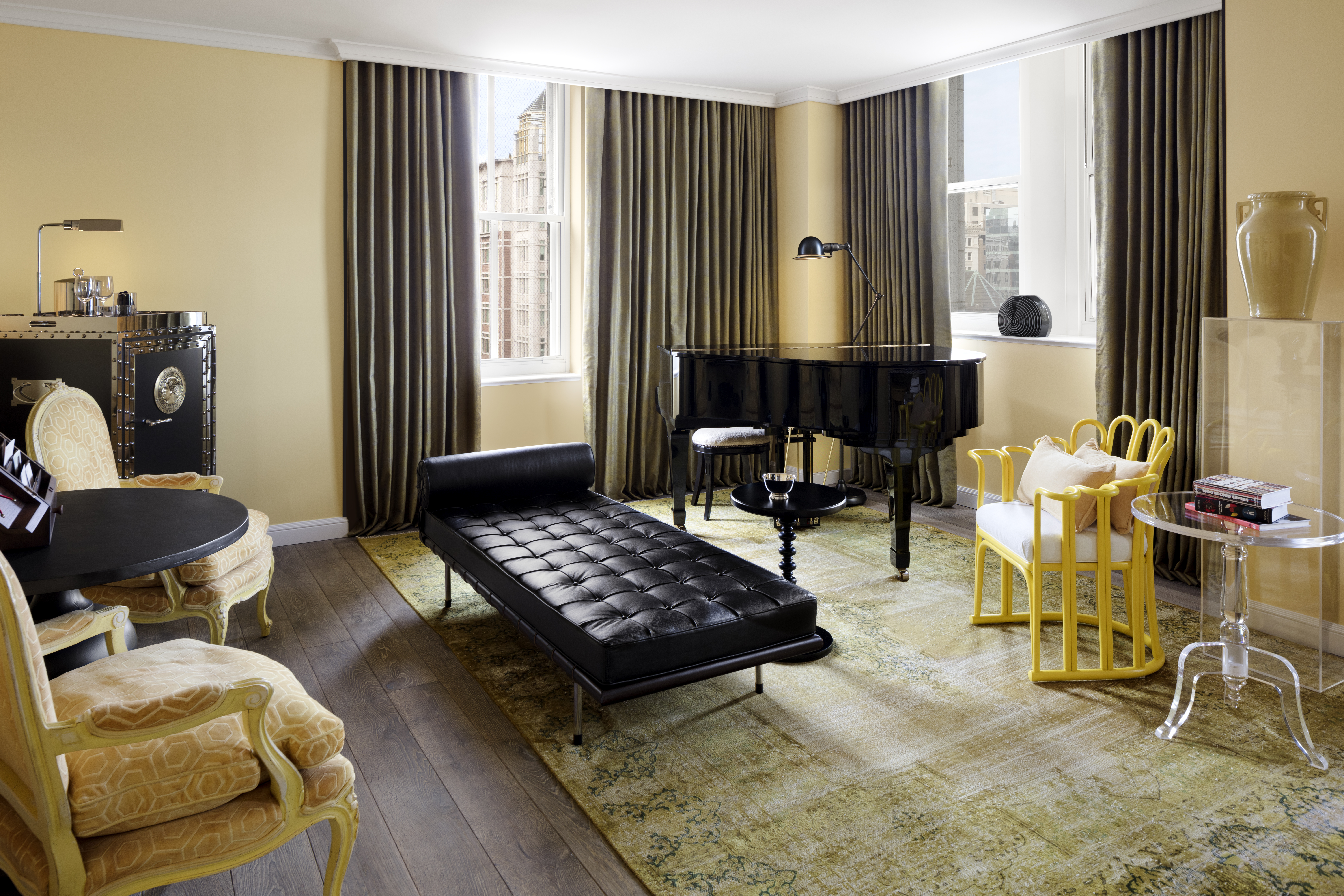 The living room of the First Lady Louisa Adams suite at Riggs DC showcases historical decor, a black piano and plush seating.