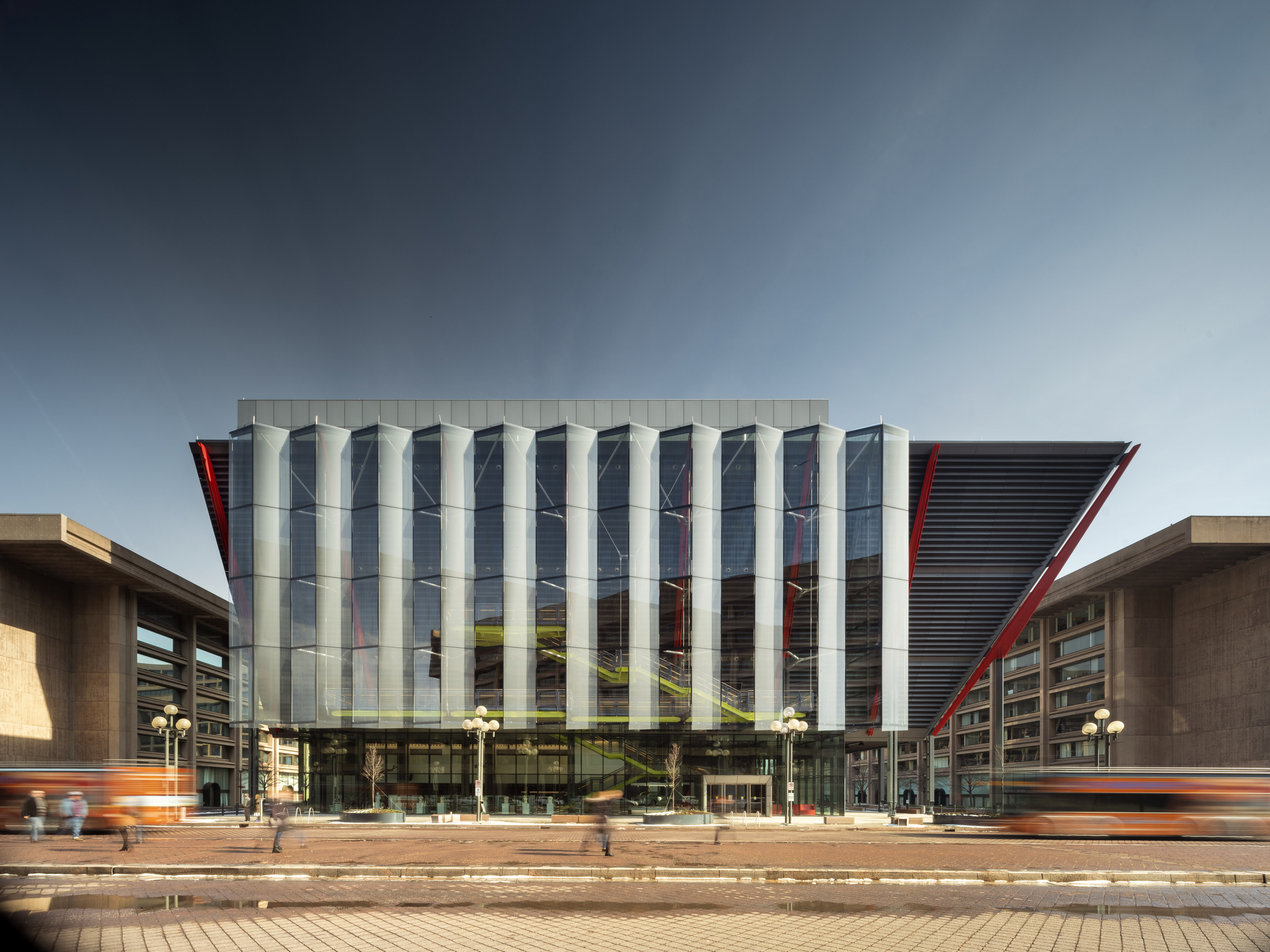 A large building with a glass facade and red accents