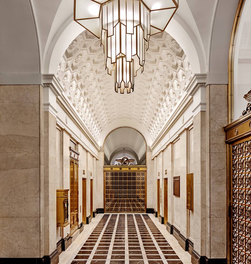 A grand lobby with a high, arched ceiling, marble walls, and a large chandelier.