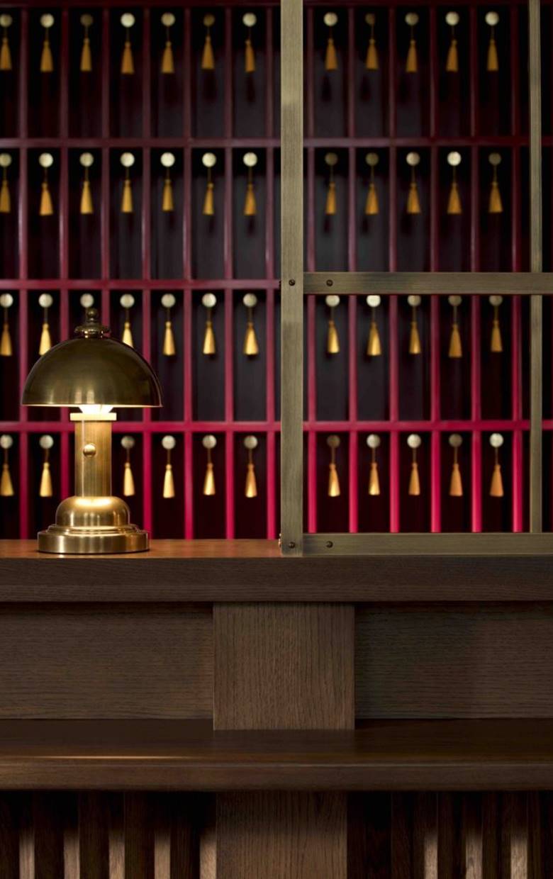 A set of vintage-style red keys with brass accents laid on a dark surface behind the desk at Riggs DC.