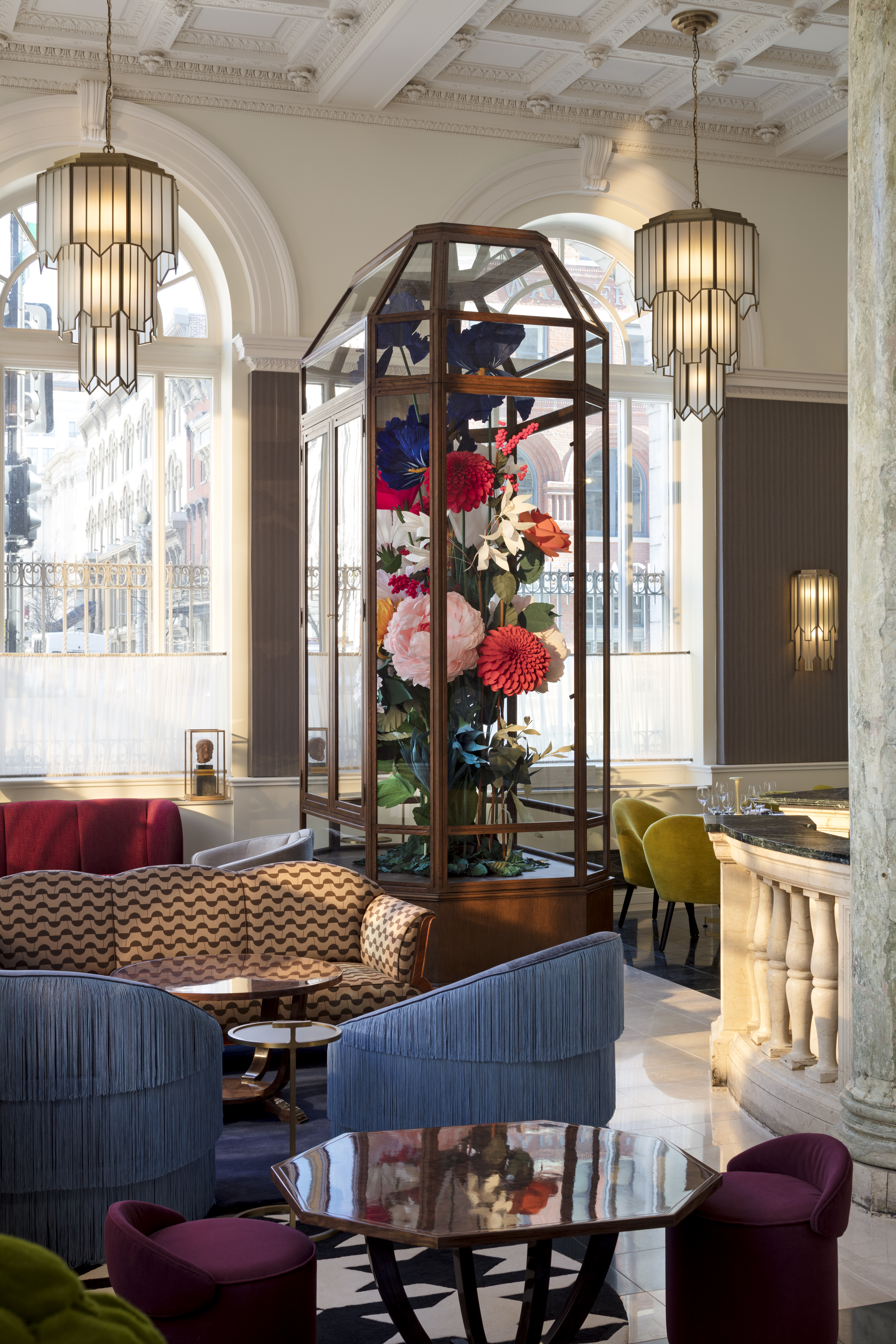 A hotel lobby with a large floral display, comfortable seating, and elegant lighting.