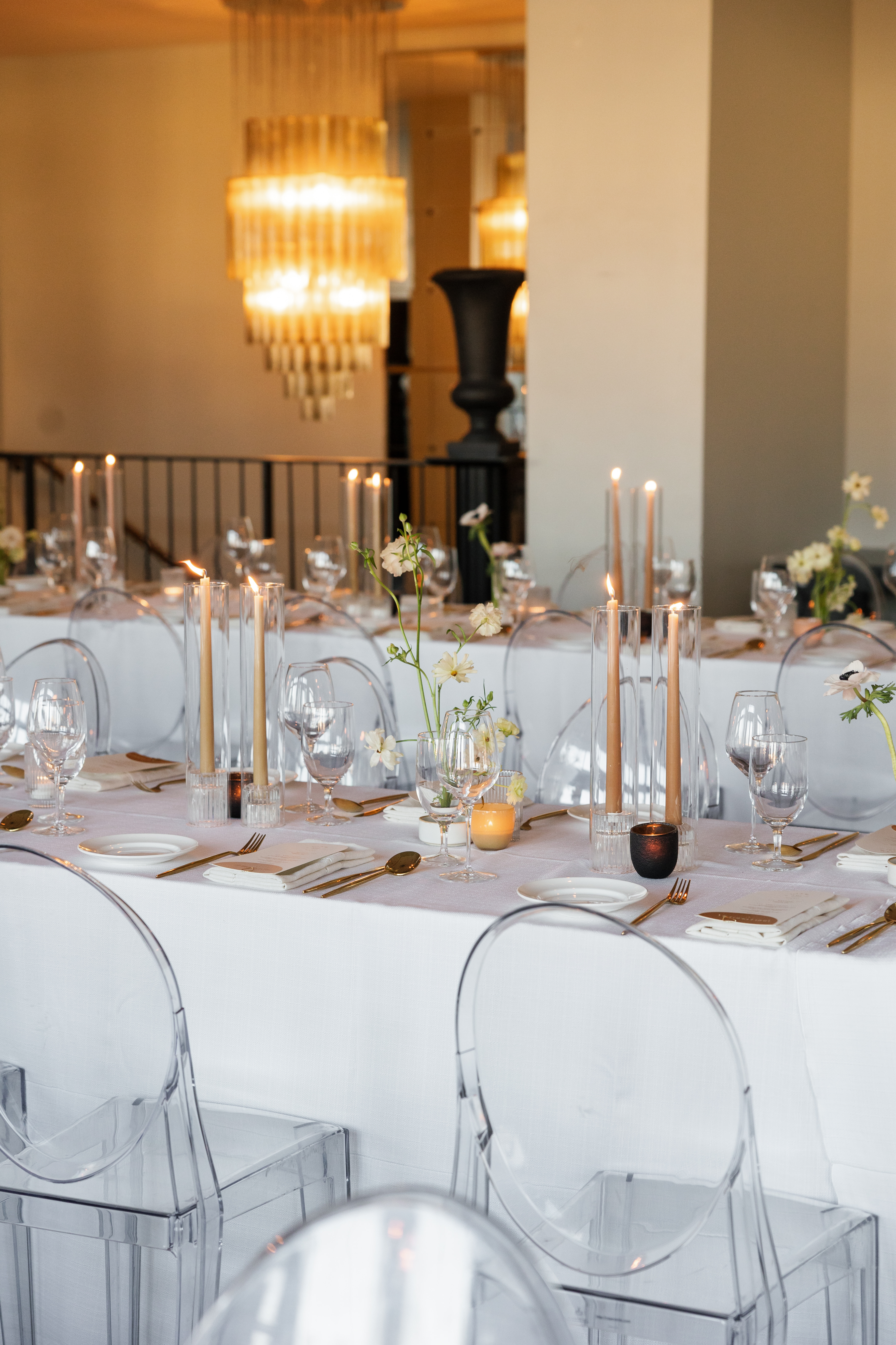 A formal dining table set with candles, flowers, and fine china in a luxurious room with a chandelier.