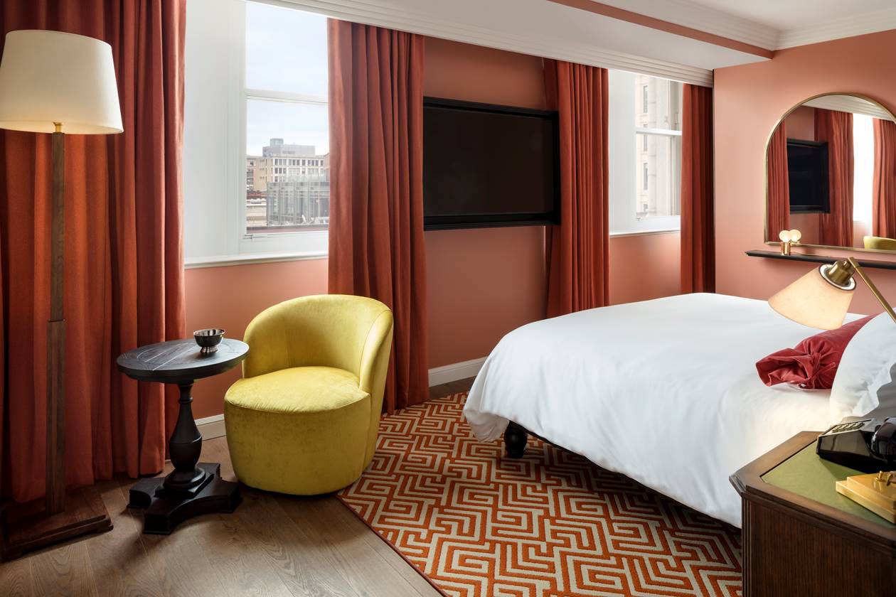 A corner of a bedroom at Riggs DC, featuring a stylish green chair and view of the city.