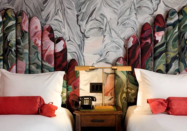 Close-up of twin beds with floral headboards and a shared wooden nightstand in a luxury hotel room at Riggs DC.