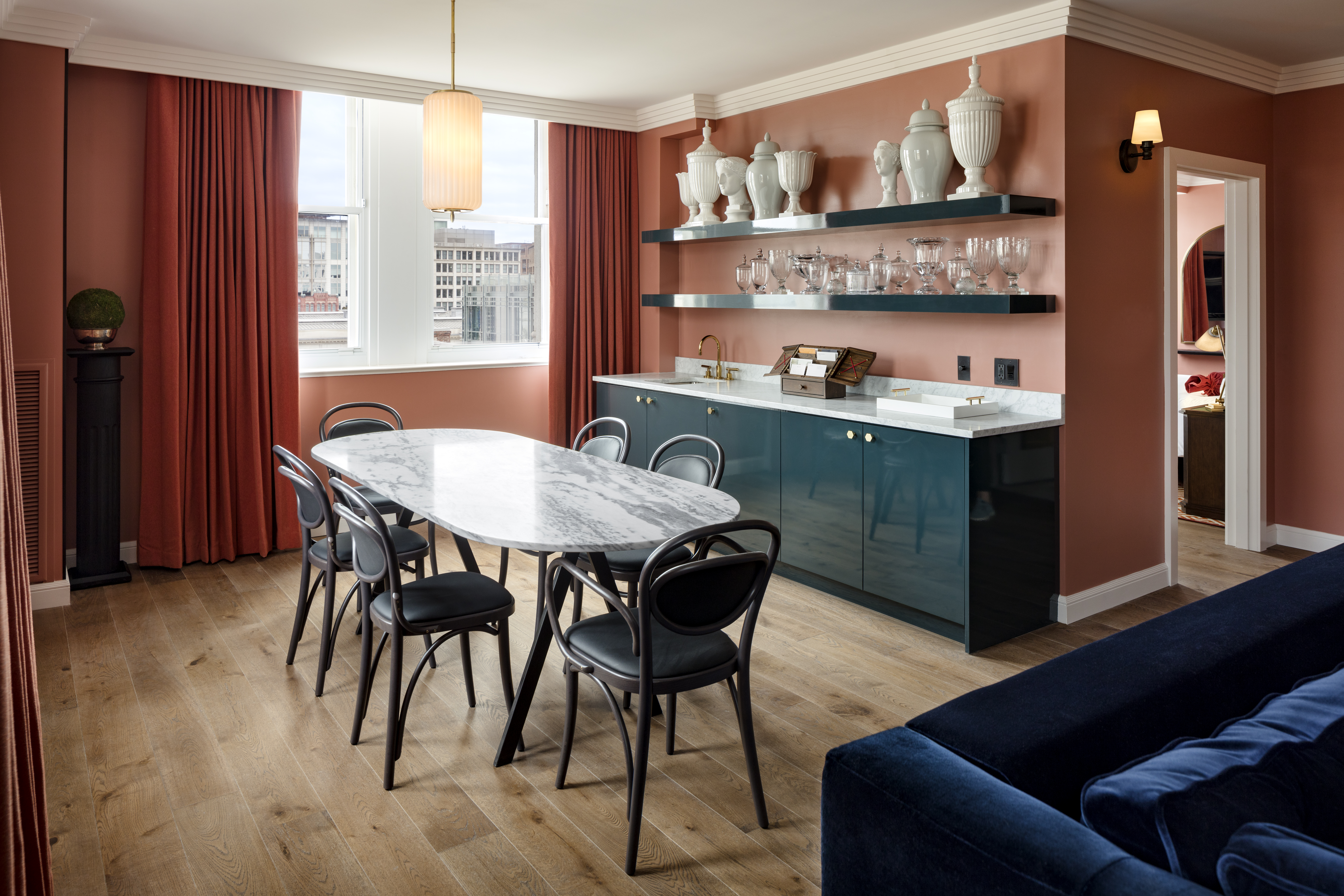 An elegant dining table in the Gallery Suite at Riggs DC, with sophisticated decor and marble art pieces on the shelves.