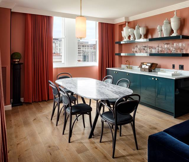 An elegant dining table in the Gallery Suite at Riggs DC, with sophisticated decor and marble art pieces on the shelves.