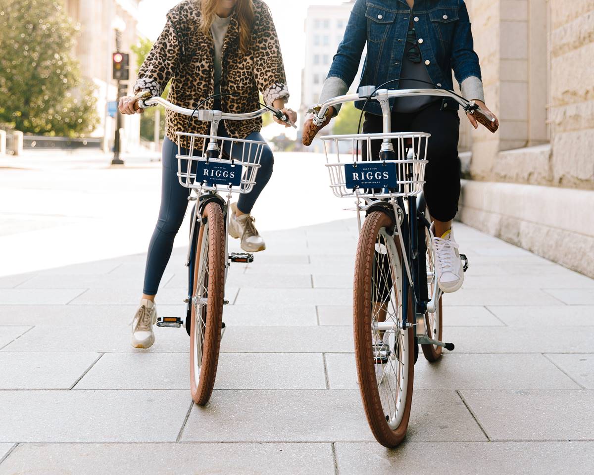 A set of stylish bikes available for guests at Riggs DC, set against a backdrop of a city street in Washington DC.