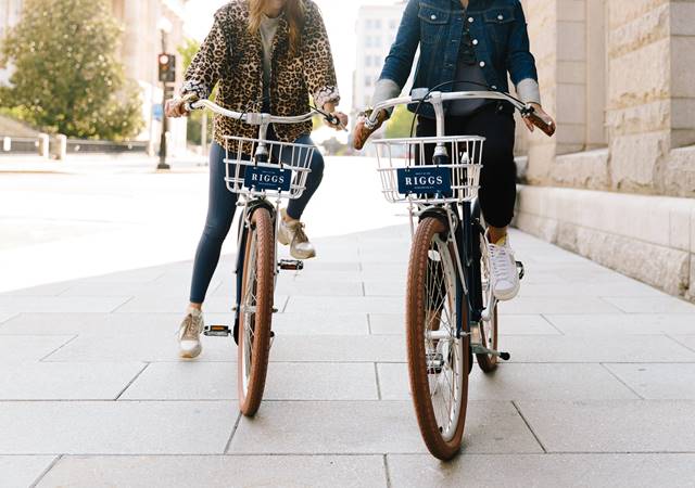 A set of stylish bikes available for guests at Riggs DC, set against a backdrop of a city street in Washington DC.