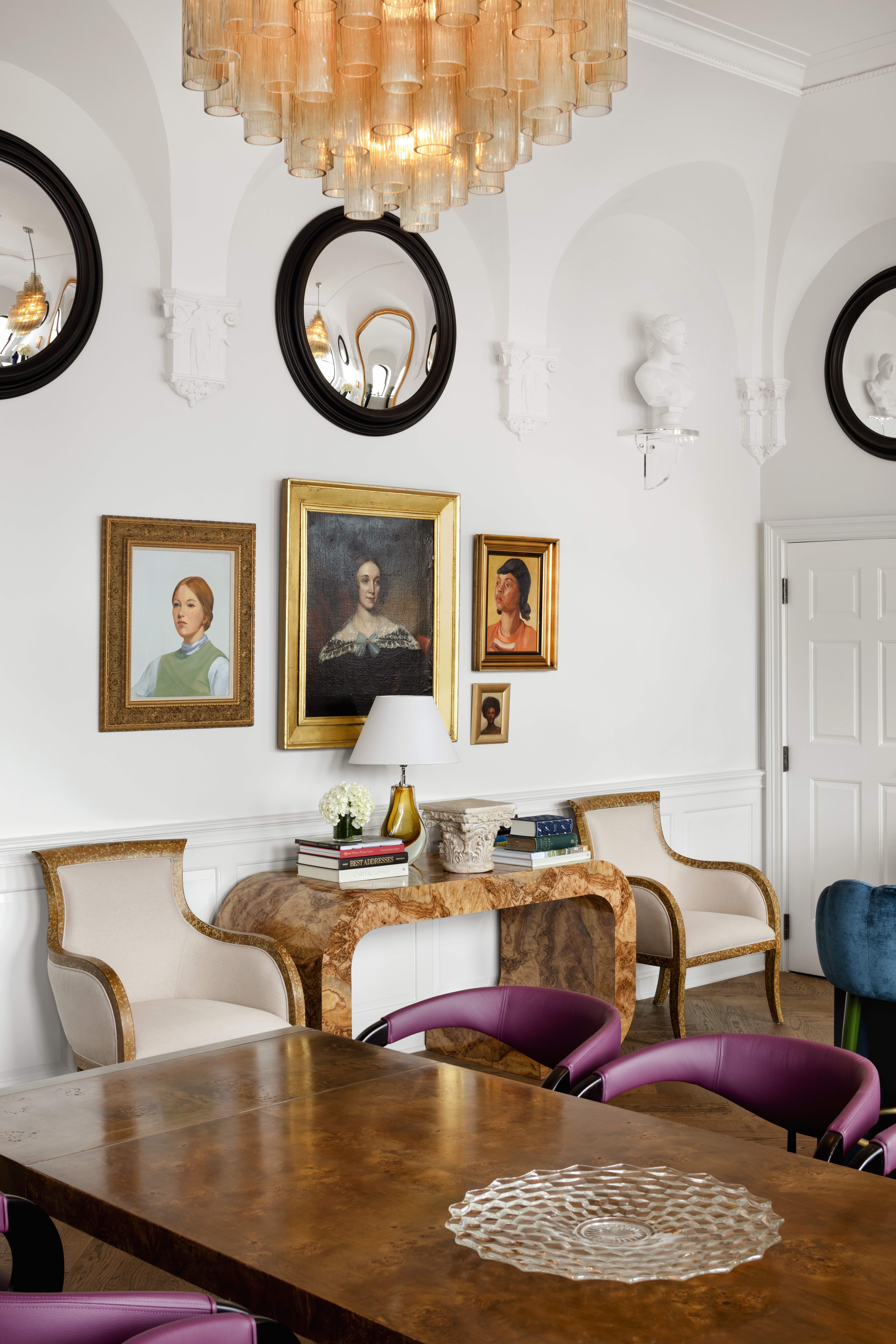 A design detail at Riggs Suite with paintings on the wall, elegant decor, a table and comfortable chairs.