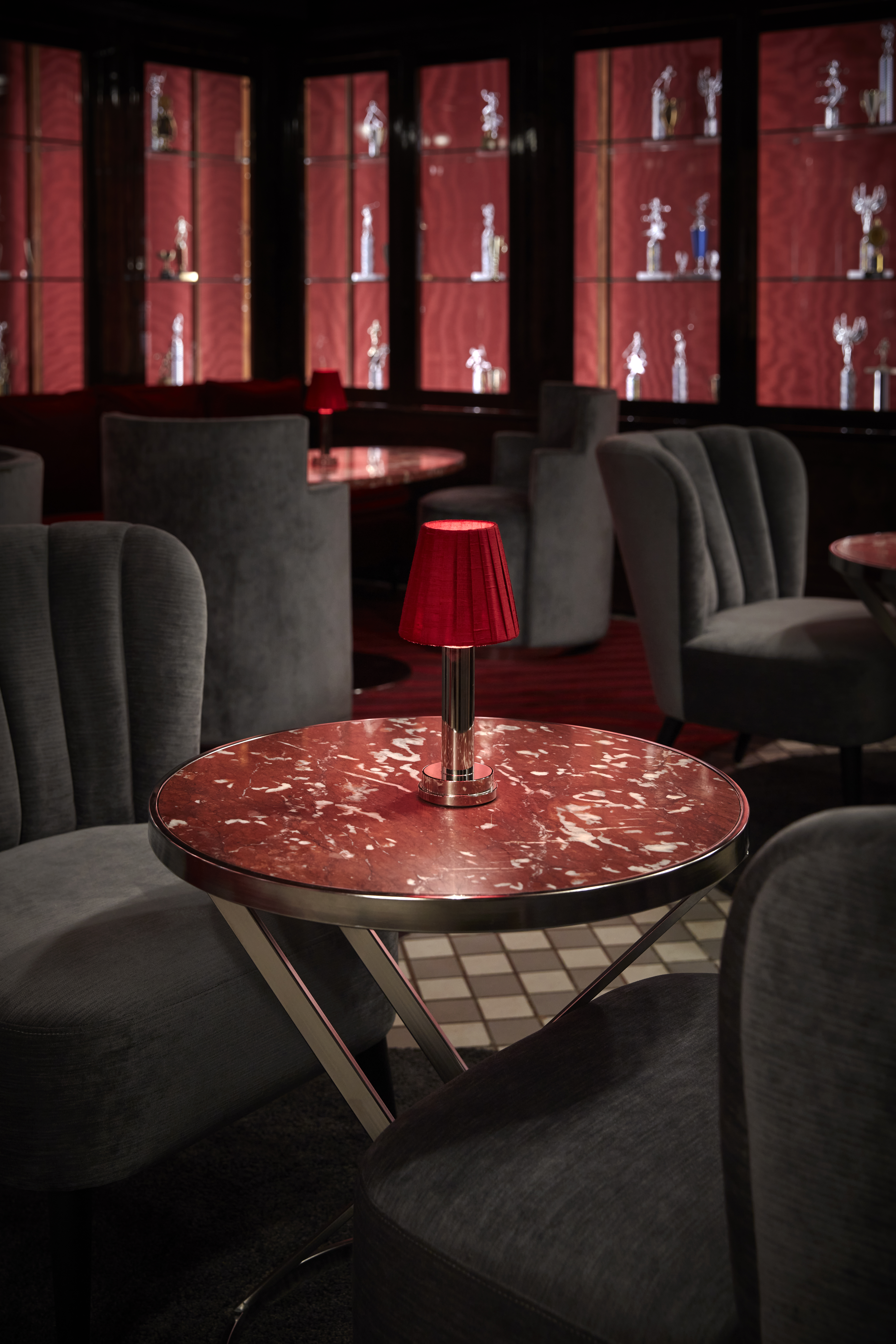 Intimate setting at Silver Lyan bar, featuring ambient lighting and elegant decor with a red lamp on a table and grey chairs.