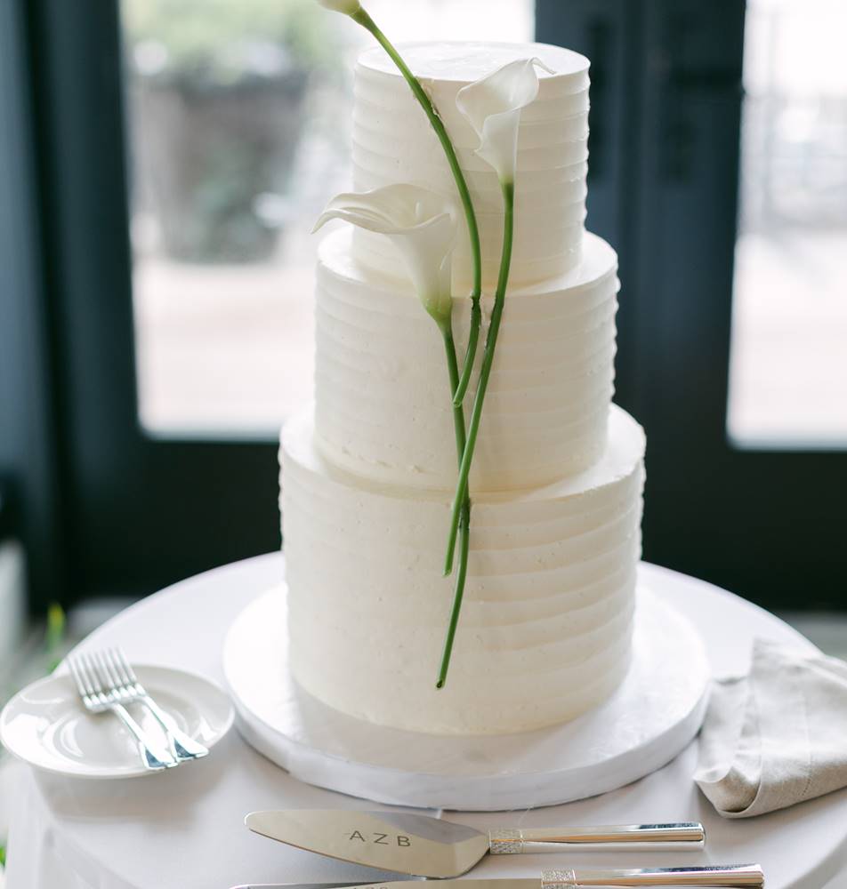 A three-tiered white wedding cake with flowers on top