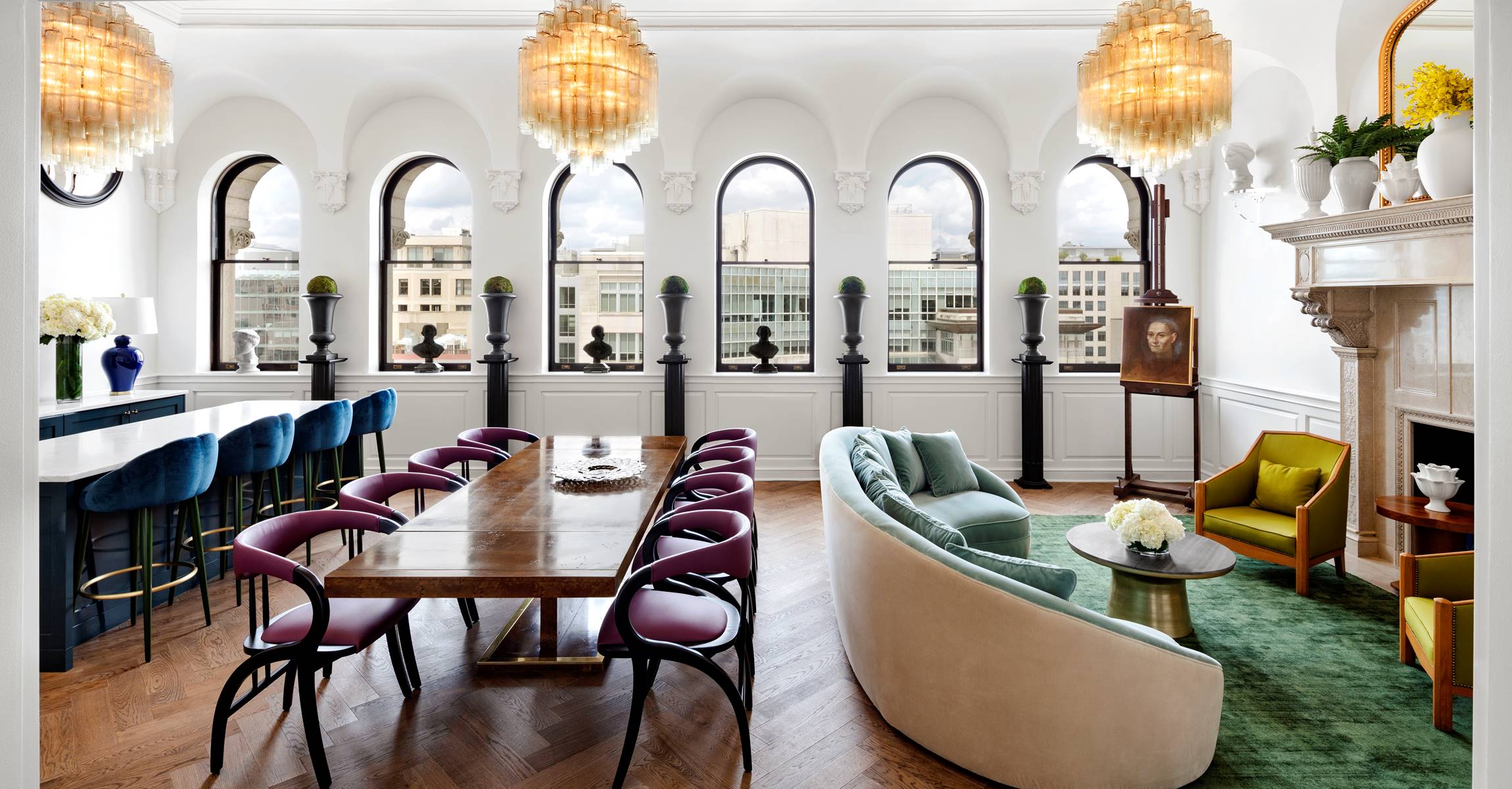 A luxurious lobby with a dining table, seating area, fireplace, and arched windows.