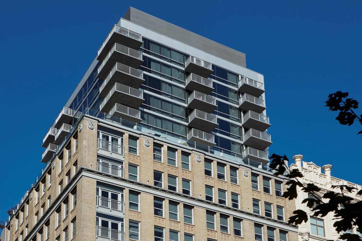 View of the modern building of Hotel Park Ave NYC with balconies stacked over a historic brick façade.