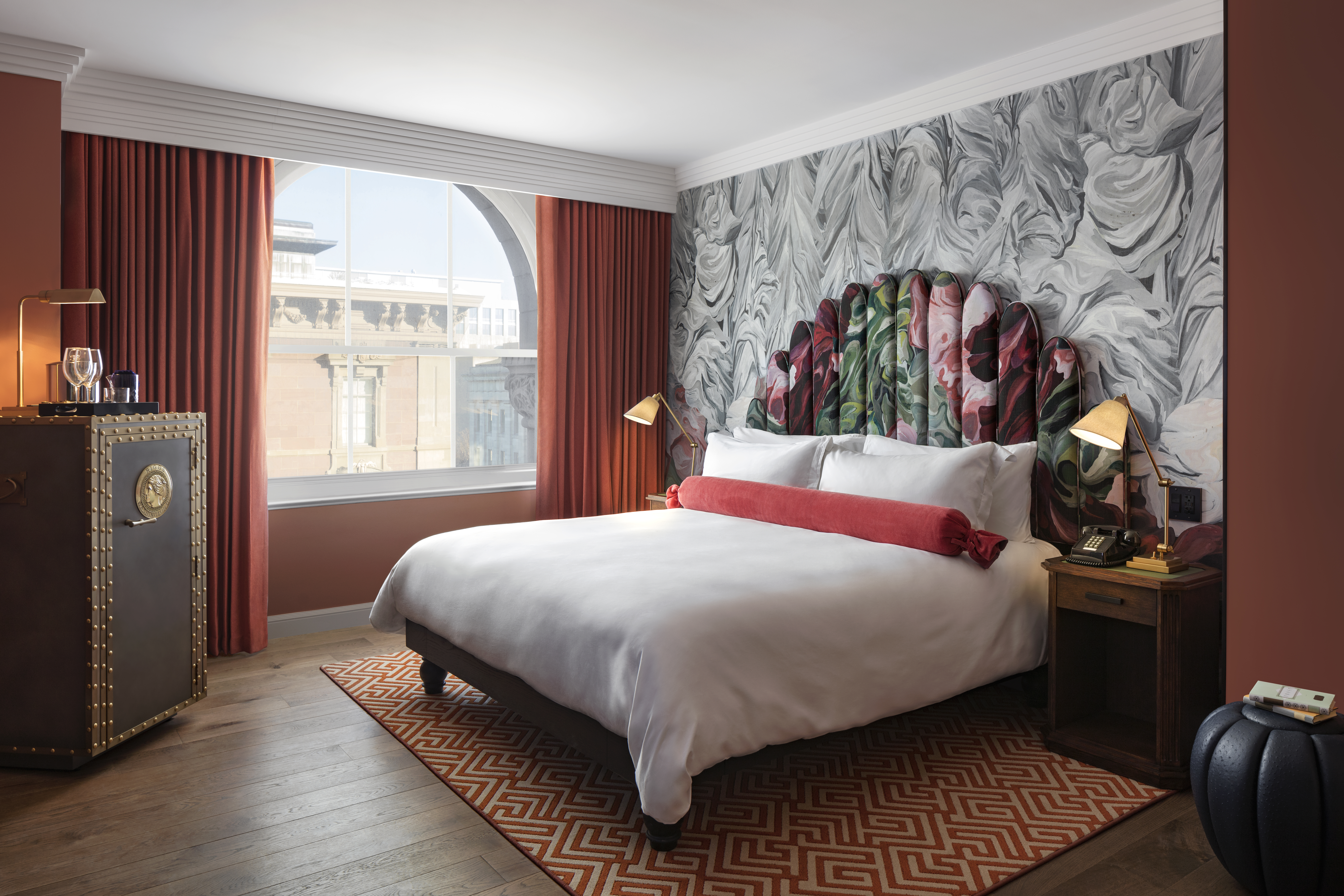 A deluxe guest room with a king-size bed, stylish decor, and large windows letting in natural light at the Riggs DC hotel.