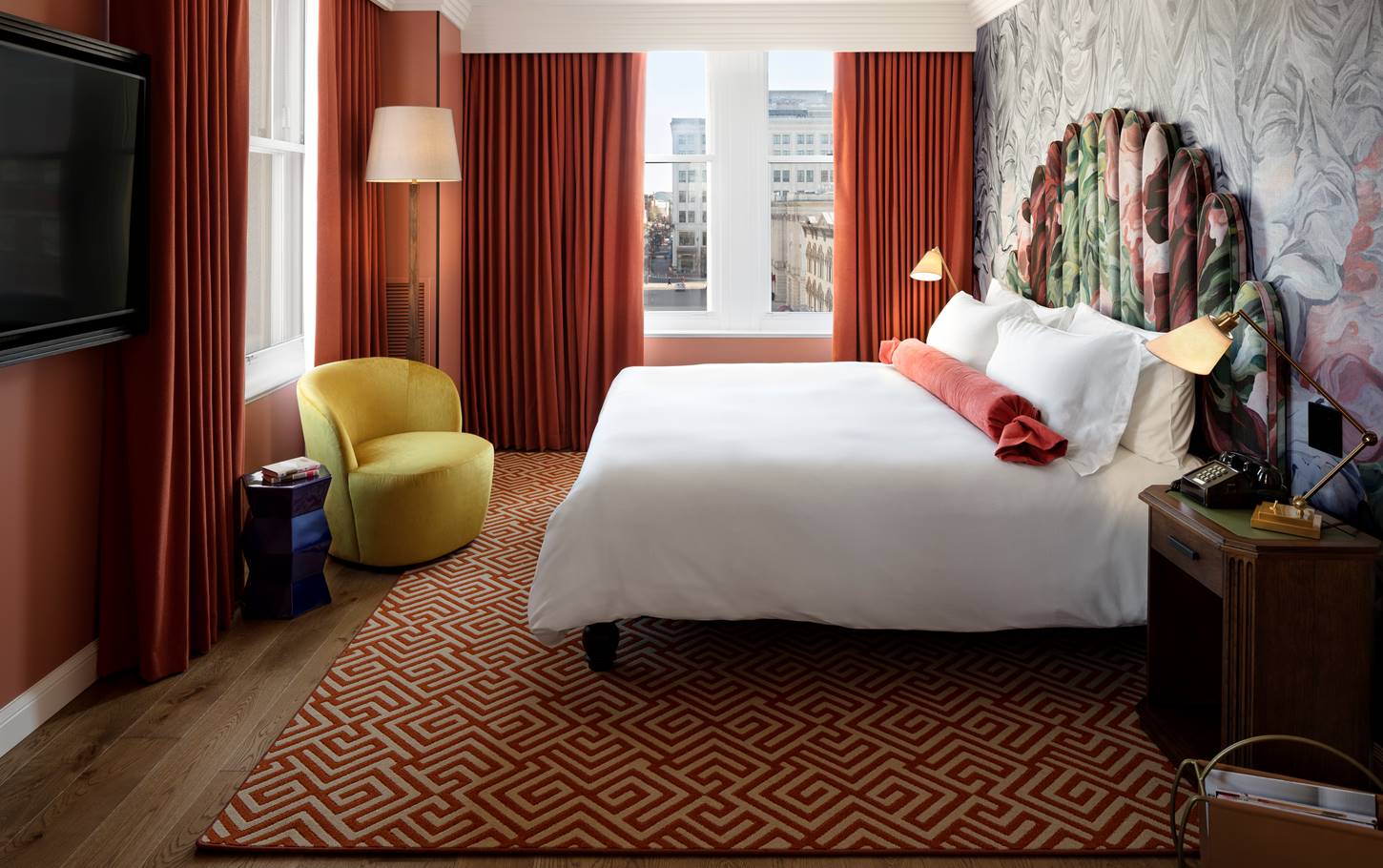 A deluxe king room with modern decor, large windows, and a comfortable seating area offering a city view at Riggs DC.