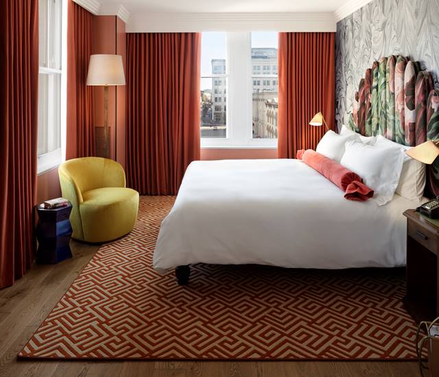 A deluxe king room with modern decor, large windows, and a comfortable seating area offering a city view at Riggs DC.