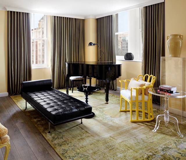 The living room of the First Lady Louisa Adams suite, decorated elegantly, showcasing the grand piano and leather seating.