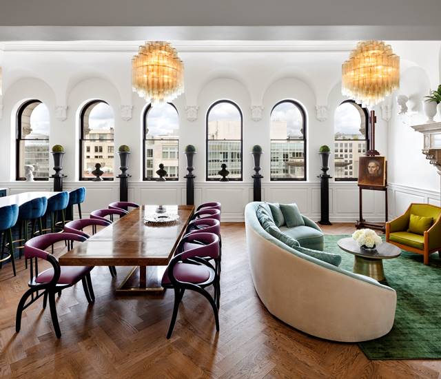 The Riggs Suite, showcasing a spacious layout with luxurious furnishings, three chandeliers and modern decor.