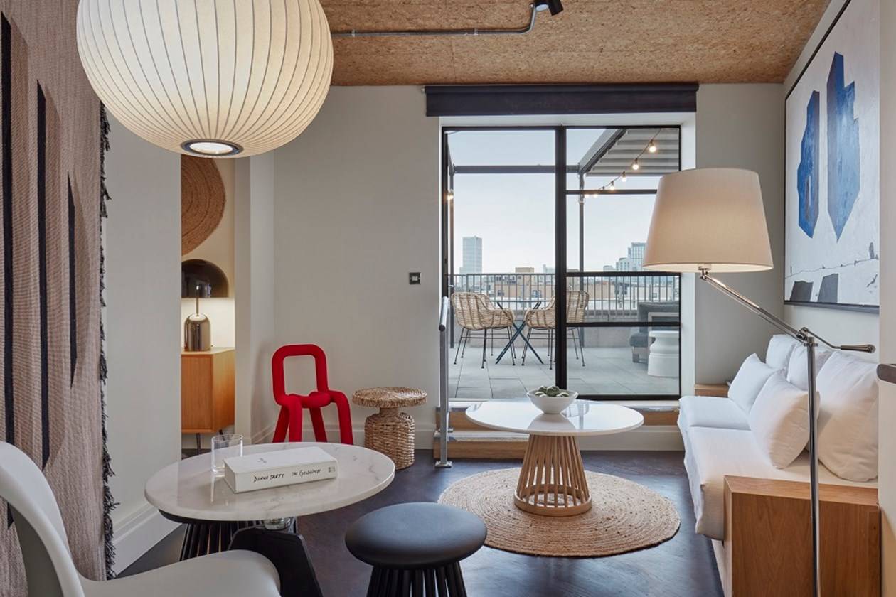 A modern living room with minimalist decor features a white sofa, a balcony view, and natural wood accents.